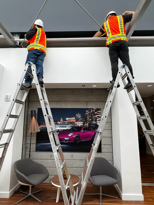 Two installers fitting a commercial shade scope in a finished interior