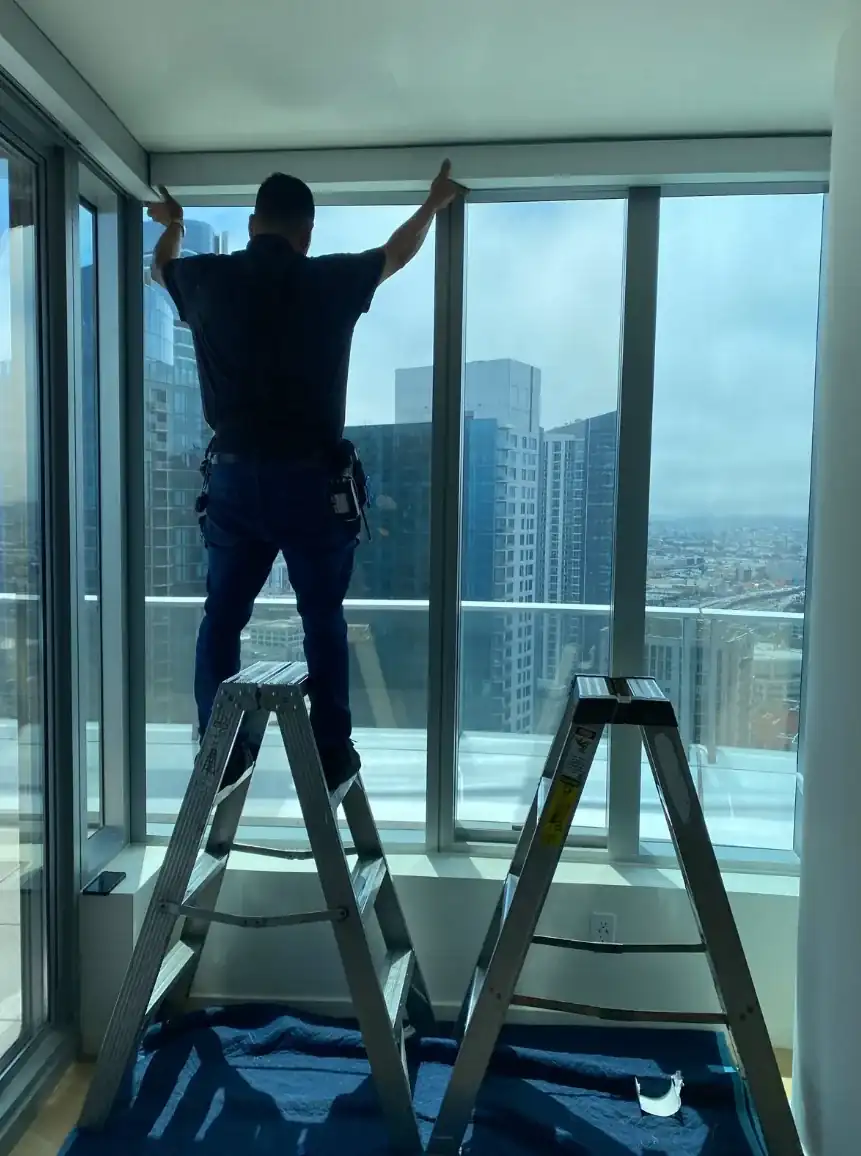 Alro installer measuring a shade at a city-facing window
