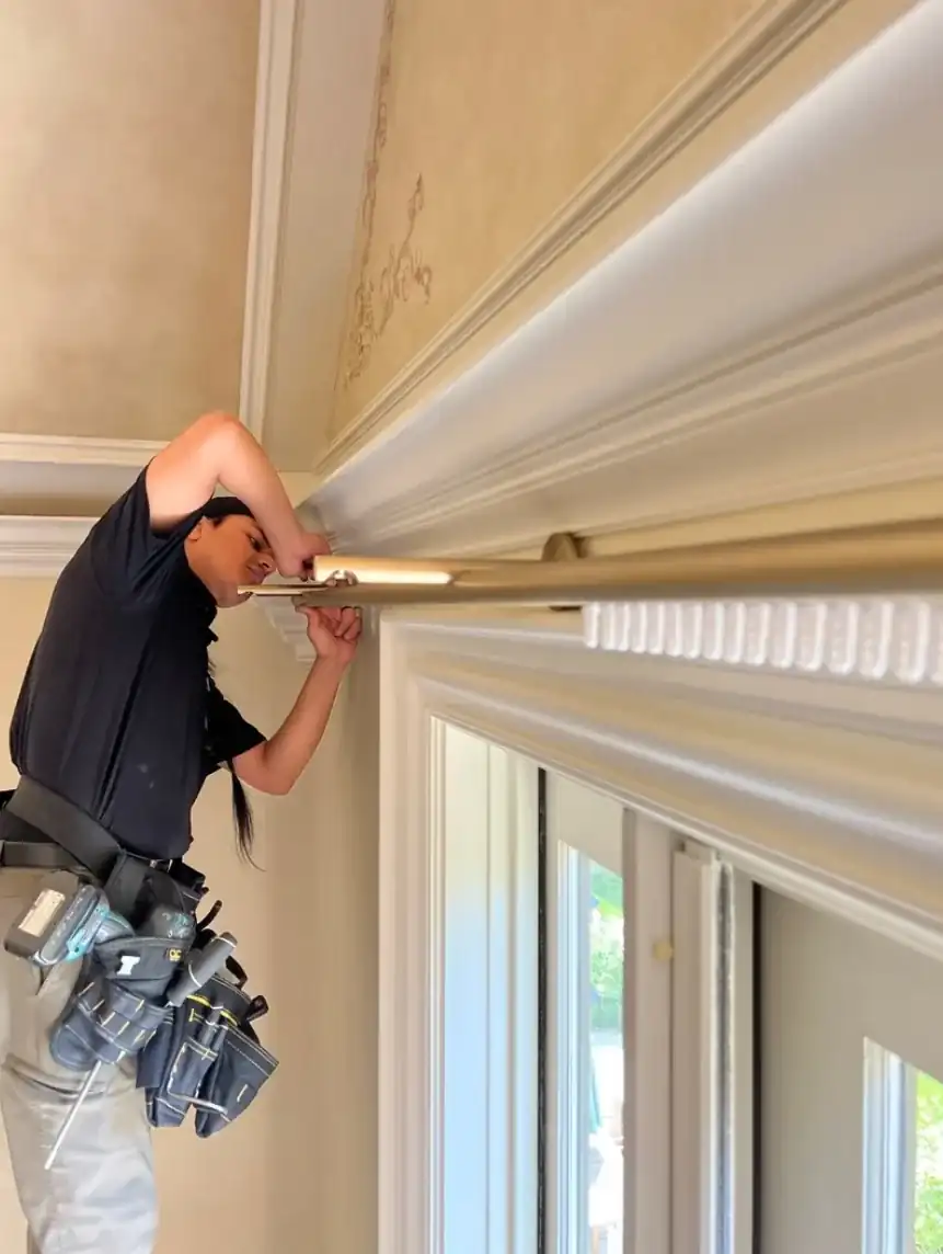 Alro installer fitting drapery hardware at a detailed interior opening