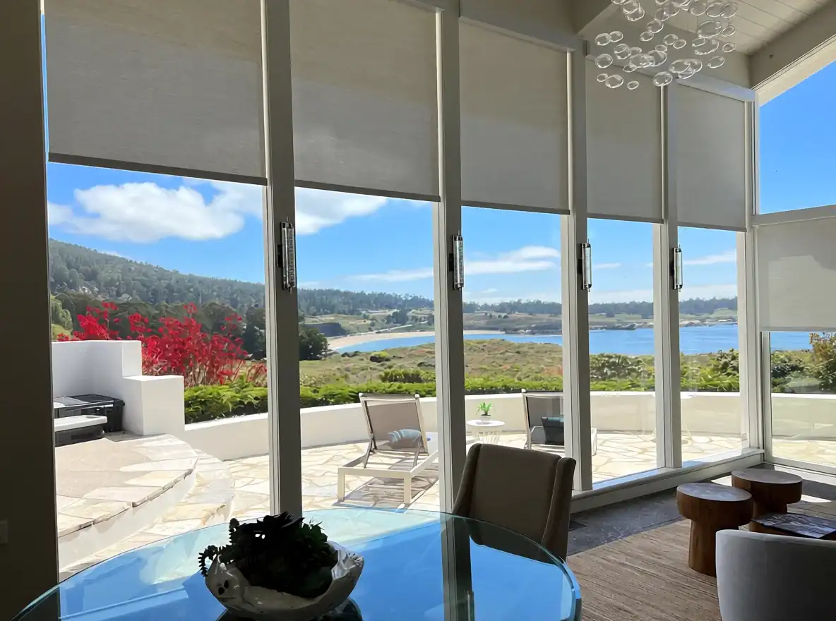 Motorized roller shades framing a bright coastal view